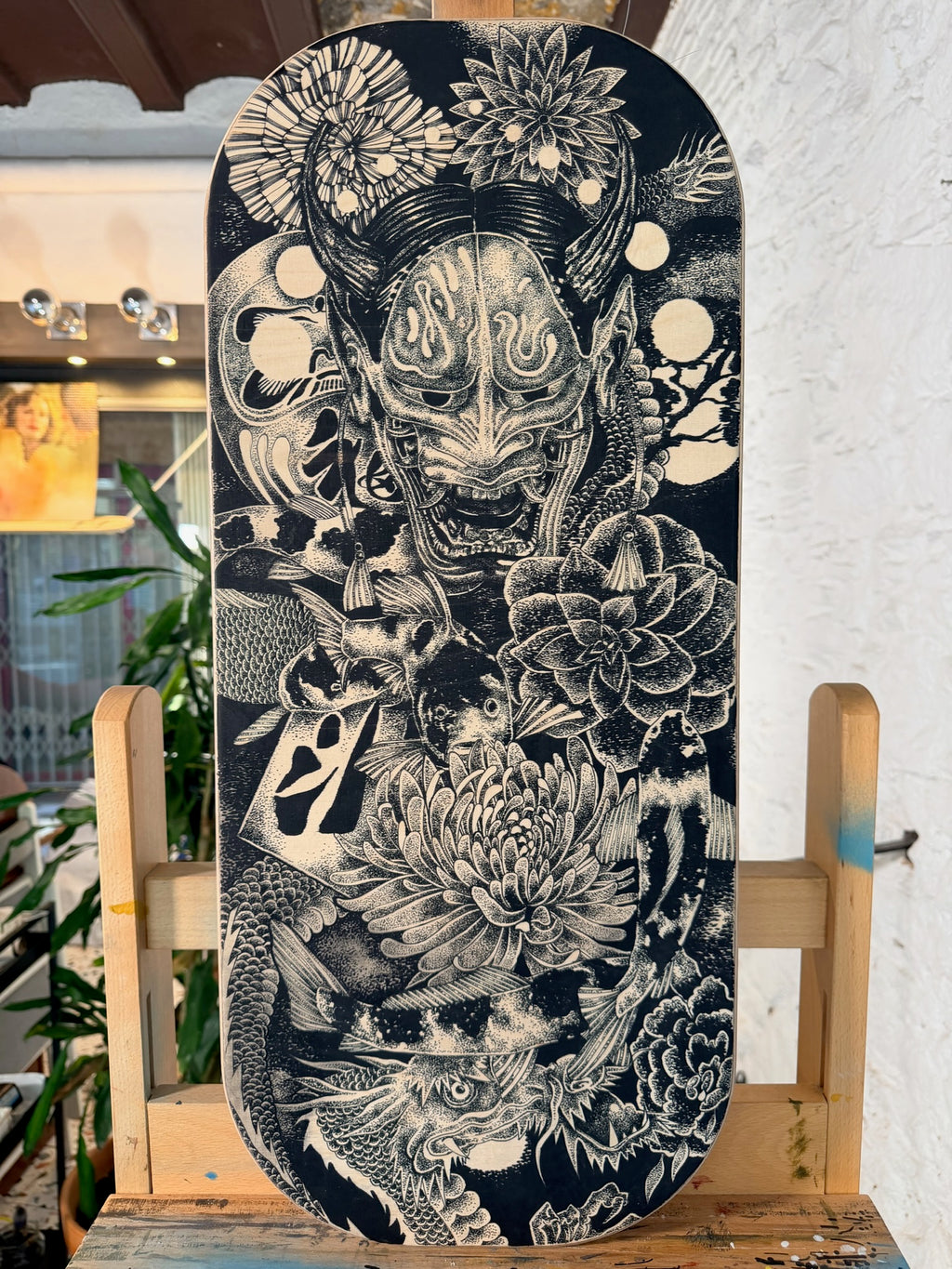 Obra original de Teixi Art sobre balance board: ilustración detallada en negro de inspiración oriental con máscara tradicional japonesa y elementos de la naturaleza sobre base de madera premium
