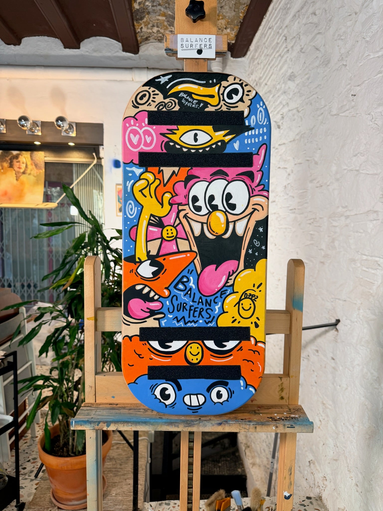 Tabla de equilibrio Balance Surfers de edición especial pintada por el artista Gozpz, con un diseño de estilo street art y personajes contemporáneos sobre madera de abedul artesanal