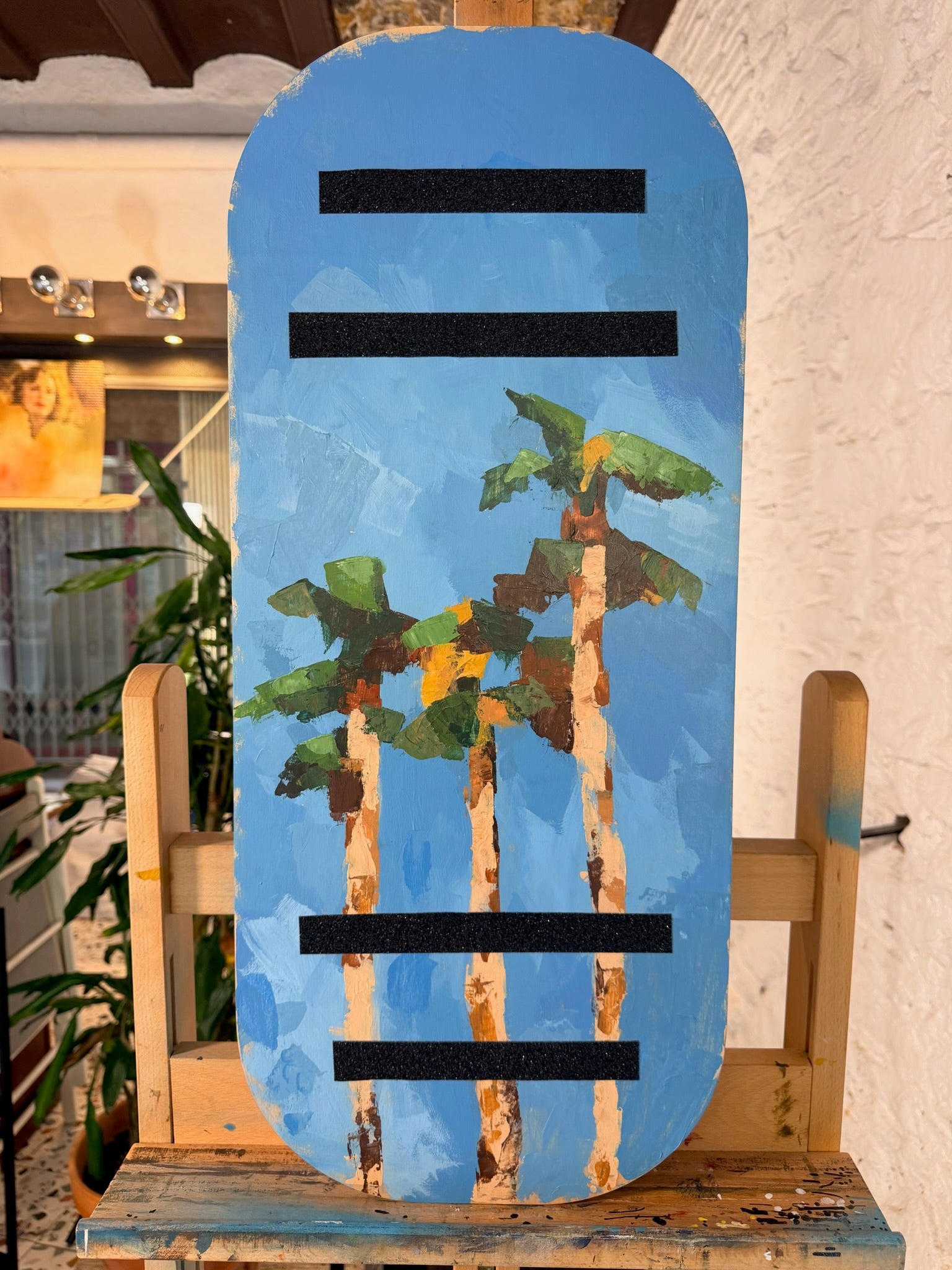 Tabla de equilibrio Balance Surfers de madera hecha a mano en taller de Barcelona. Palmeras pintadas sobre madera natural mientras la artista hacía equilibrio sobre otra balance board. 