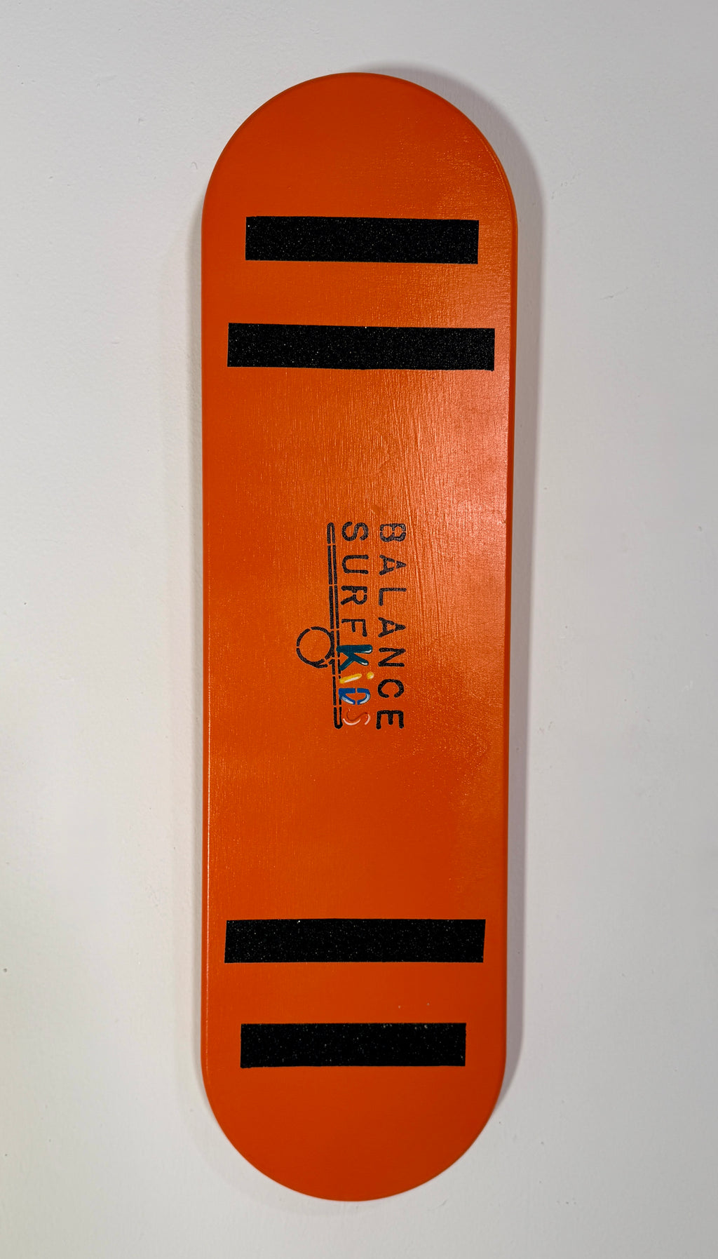 Tabla de equilibrio infantil Balance SurfKids color naranja brillante con bandas antideslizantes negras y logo central, fabricada artesanalmente en madera de abedul.